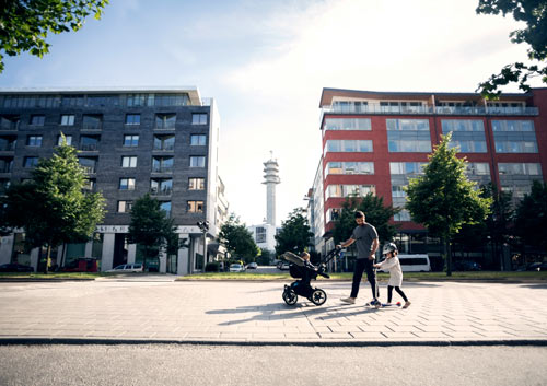 Pappa och dotter som går framför lägenhetshus
